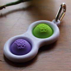 Purple-lime colorway shown on a pocket-sized fidget keychain for portable distraction management.