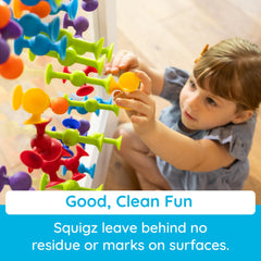 Fat Brain Toys Squigz colorful pieces on tub edge inviting exploration.