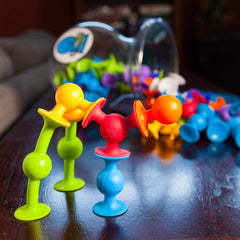 Fat Brain Toys Squigz Deluxe kids using suction on a bath wall to spark imaginative play