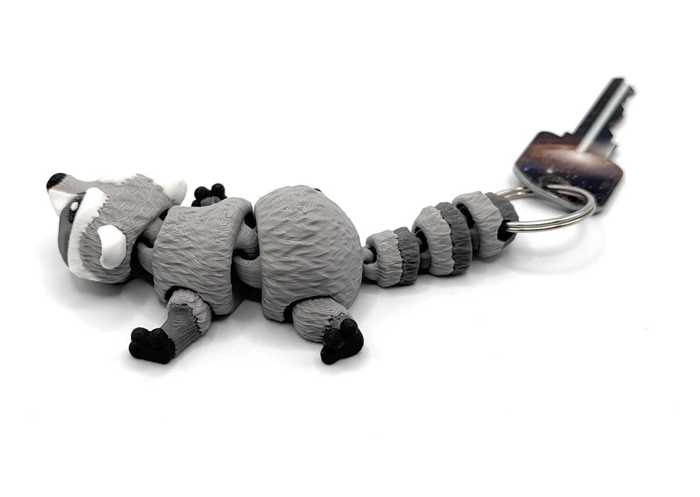 Raccoon articulating keychain in stone gray, ideal for backpacks and zipper pulls.