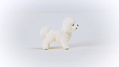 Schleich Farm World Bichon Frise figurine in a barn setting for cooperative pretend play.