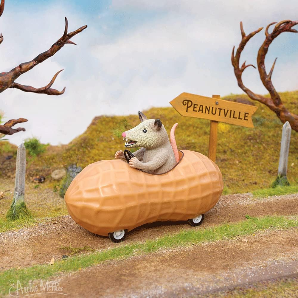 Archie McPhee possum in a peanut pull-back toy car close-up vinyl texture detail.