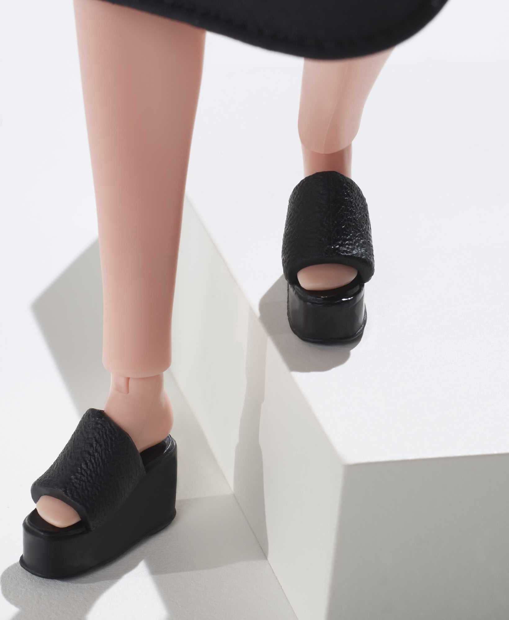 Barbie Signature Looks doll pairs black and white top with platform slides for styling.