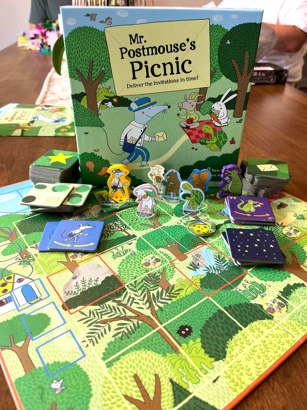 GIGAMIC Mr. Postmouse’s Picnic artwork showcases bright, whimsical village scenes.