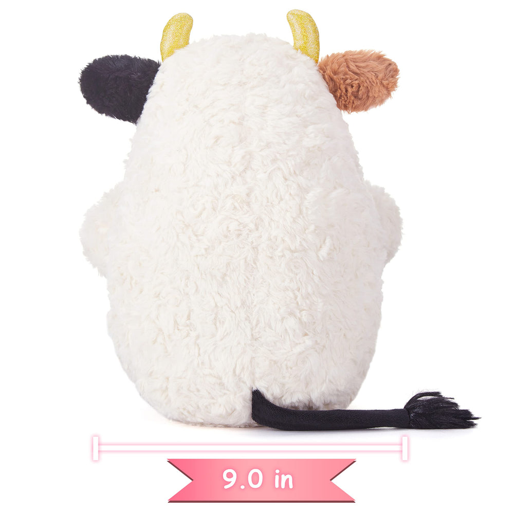IKASA cow plush displayed in a nursery or bedroom decor.