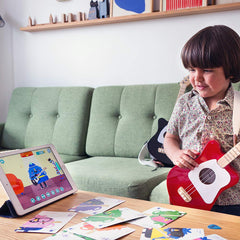 Loog Mini beginner kid playing with a proud smile.