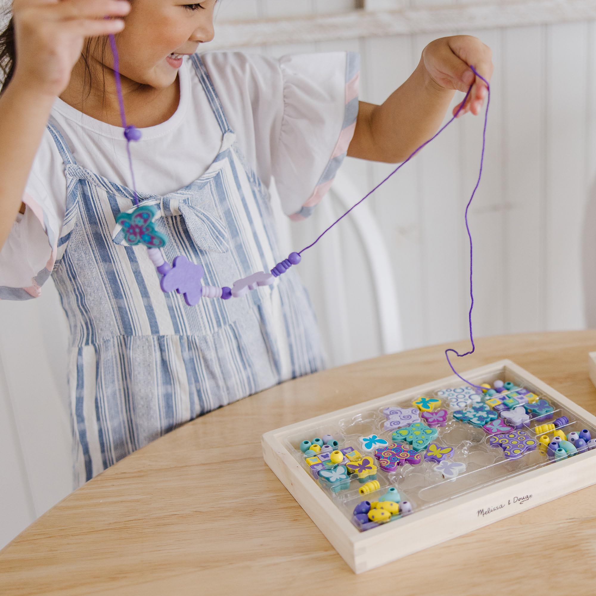 Kids string beads to design necklaces and bracelets with Melissa & Doug