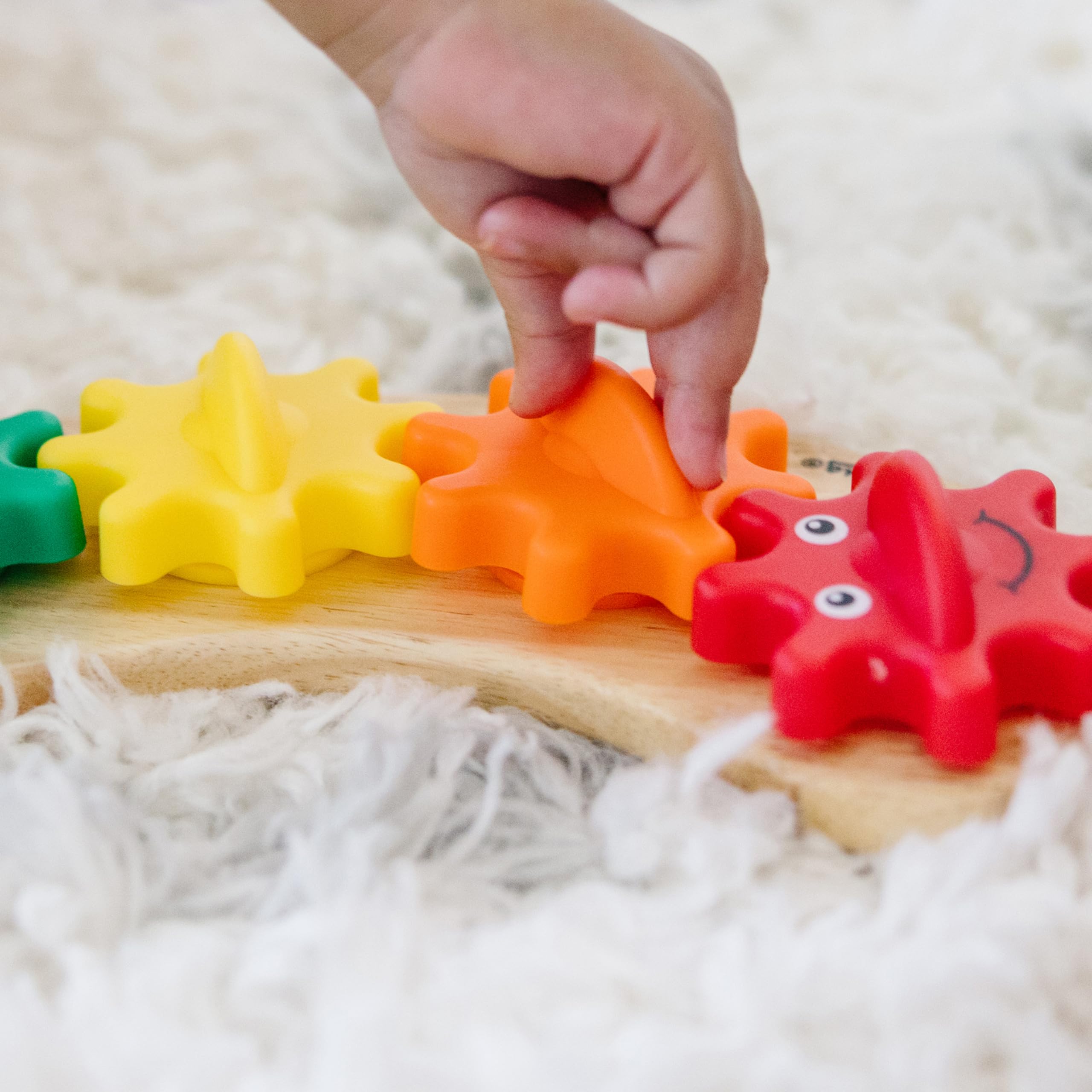 Red gear face on Rainbow Caterpillar Gear Toy adds friendly focal point for toddlers