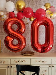 Mluchee Number 0 balloon, 40-inch red wall display, dramatic backdrop.