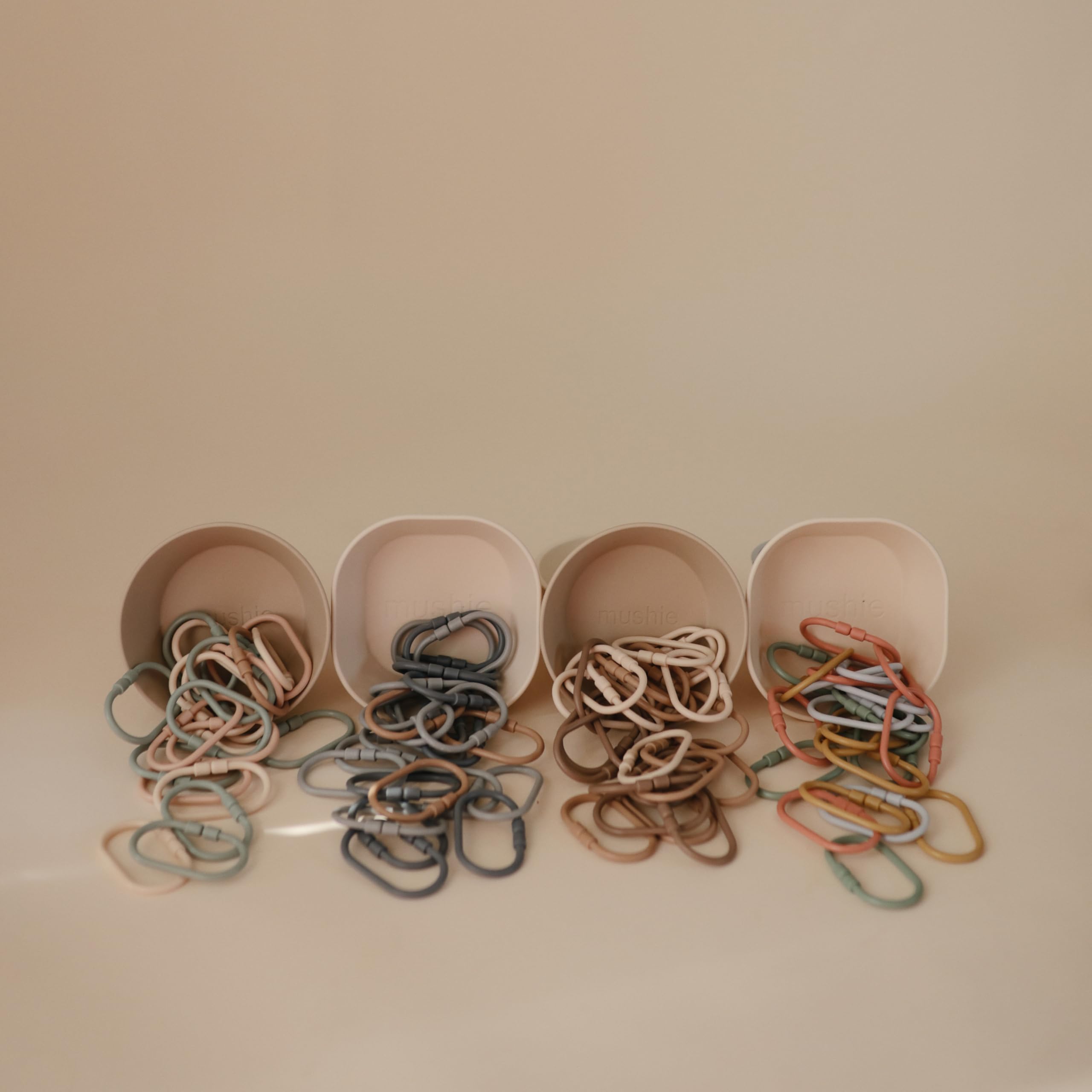 Mushie Chain Link Rings khaki color attached to a stroller for quick toy reach.