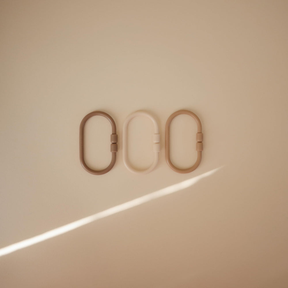 Mushie Chain Link Rings in shifting sand color support on-the-go play and easy access to toys.