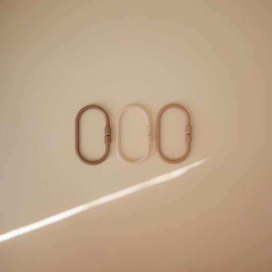 Mushie Chain Link Rings in shifting sand color support on-the-go play and easy access to toys.