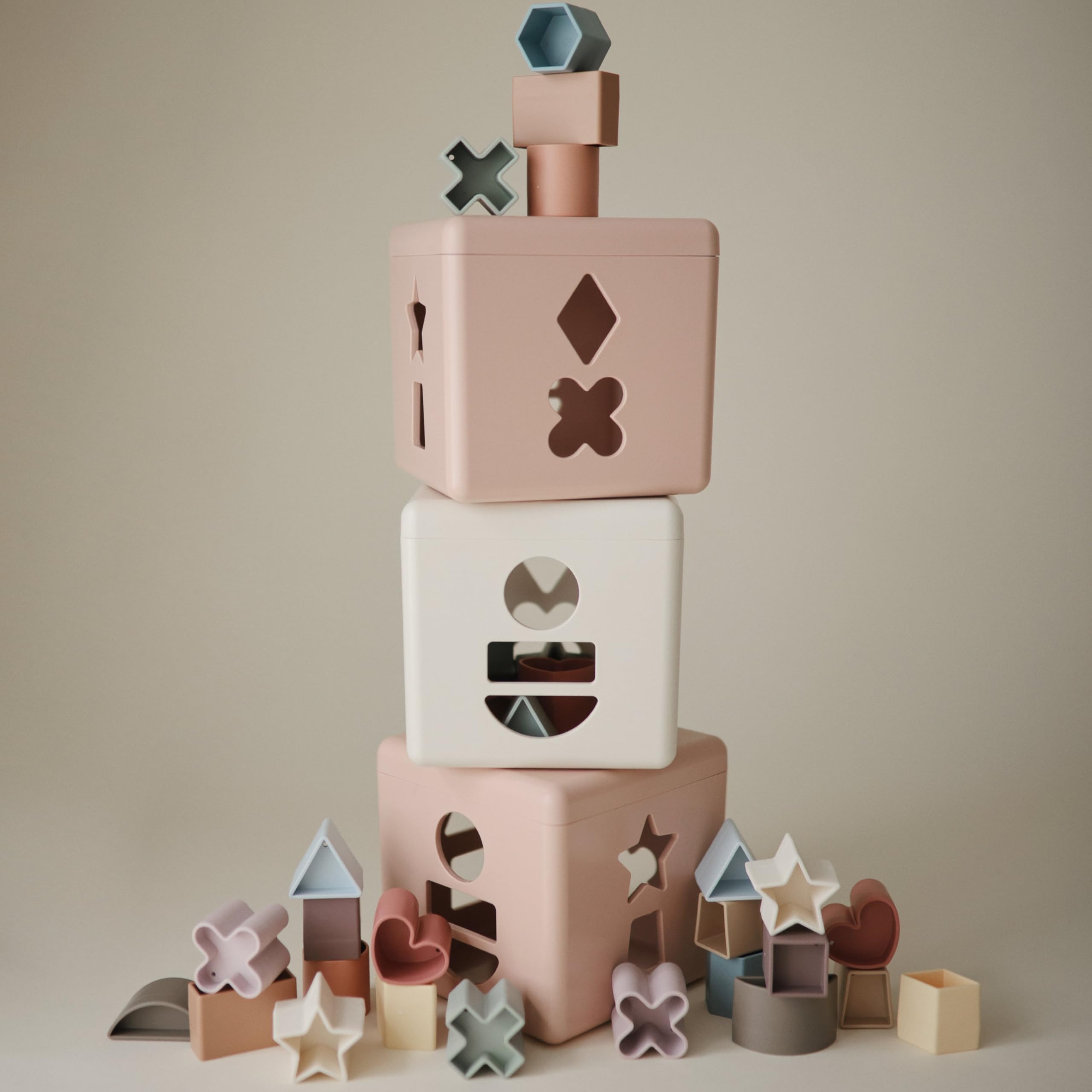 Mushie Shape Sorting Box Petal in soft colors enhances cognitive play.