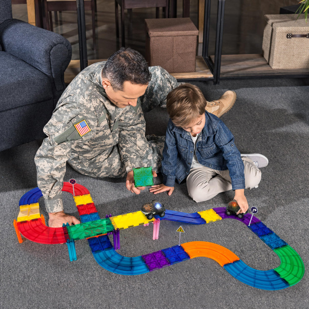 PicassoTiles dinosaur race cars speeding on a colorful magnetic track.