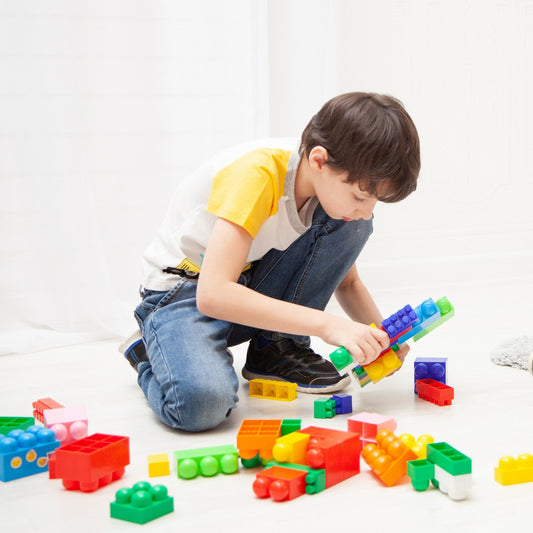 Child playing with colorful building blocks on a white floor
