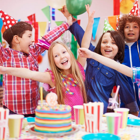 Children celebrating a birthday with a colorful cake and decorations.