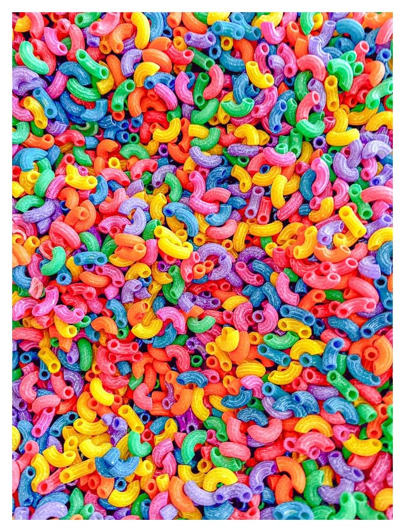 Sensory-N-Stuff rainbow elbow pasta in a bin, vivid colors for tactile exploration.