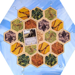 Tabletop Monthly Victim Mentality Card with Catan board, shows matching thickness and fit.