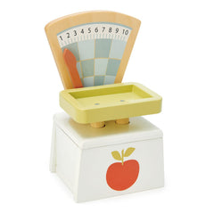 Tender Leaf Toys child using market-scale teaches weight-based pricing through imaginative play.