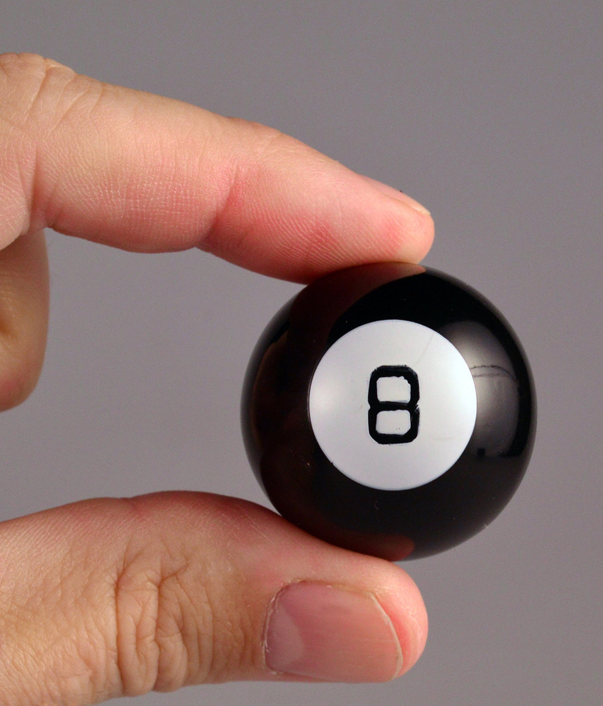 World's Smallest Magic 8 Ball on desk, tiny nostalgic fortune teller for quick fun.