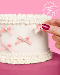 xo Fetti pink bow pearl cake topper on a cupcake display