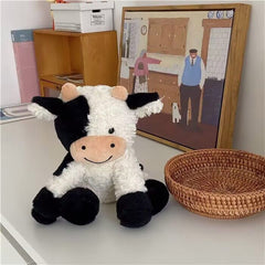 YUKOUQIAN cow sitting plush toy ready for cuddles on a bed.